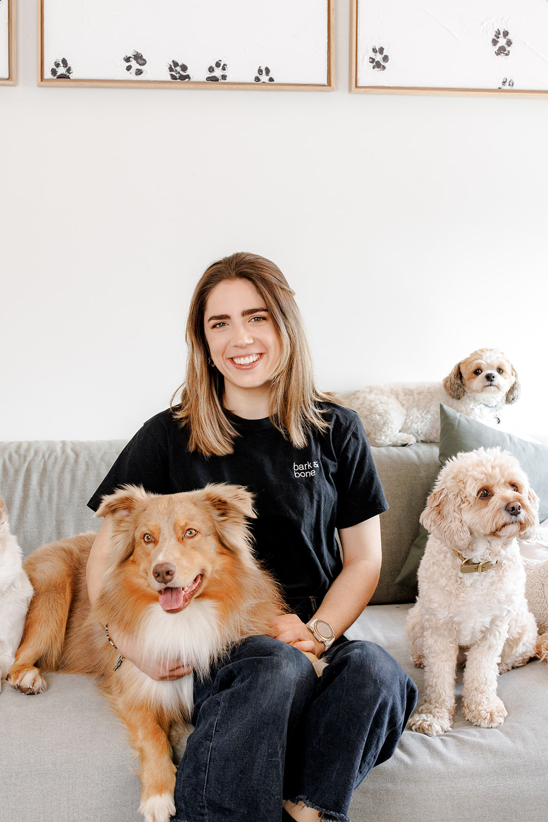Agnieszka Koc smiling, sitting on a sofa with three dogs