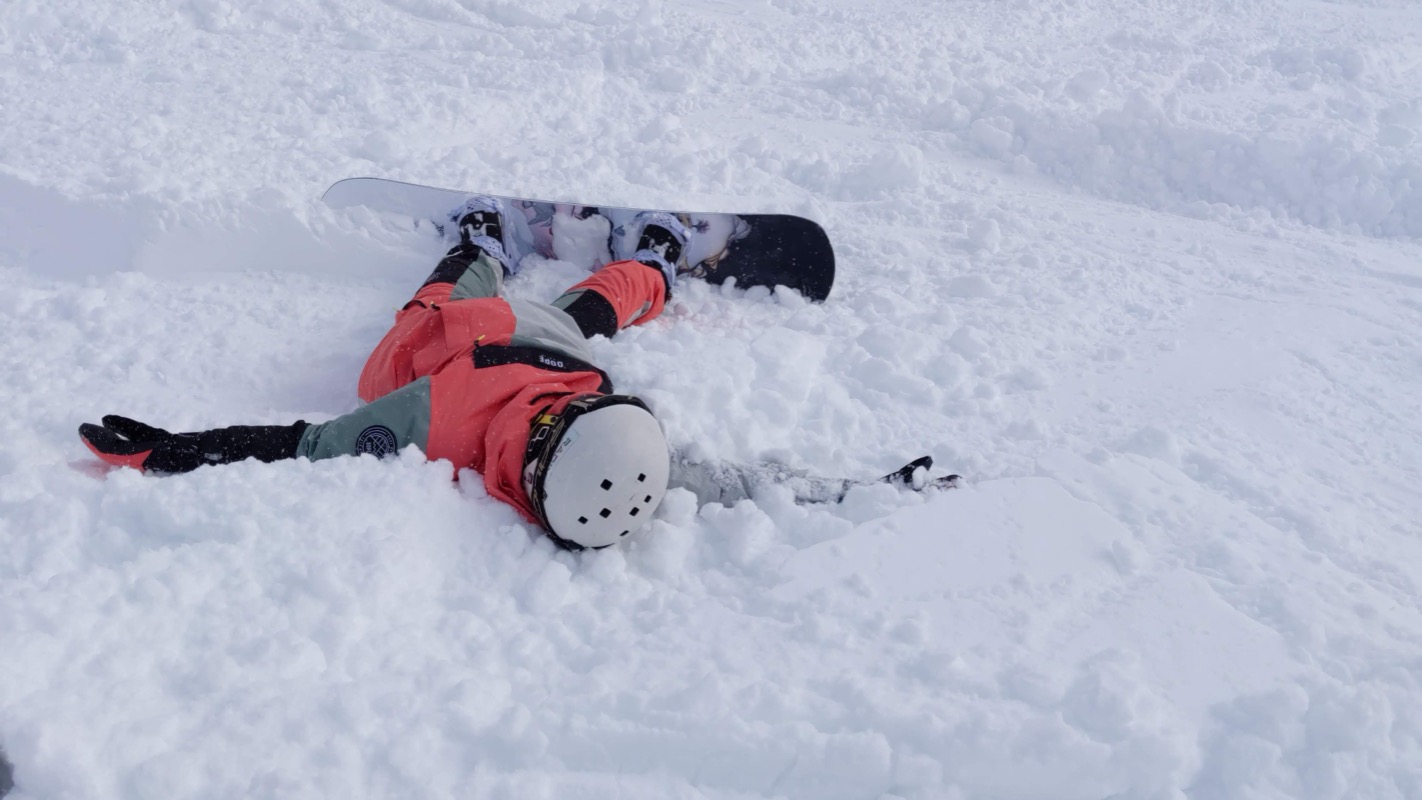 Lying in powder snow after a snowboard wipeout